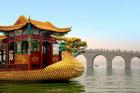 The Summer Palace, a traditional Dragon Boat passes the Seventeen Arch Bridge, Kunming lake, Beijing, China