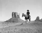 Navajo Indian In Cowboy Hat On Horseback With Monument Valley Rock Formations In Background