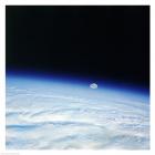 Outer space shot of storm system in early stage of formation with moon in background