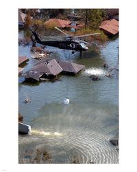 A Blackhawk helicopter drops sandbags into an area where the levee broke due to Hurricane Katrina | Obraz na stenu